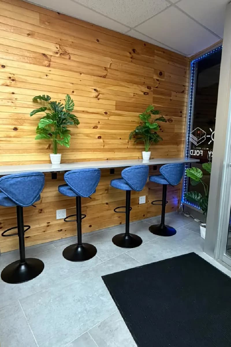 Wooden counter with blue stools by the window, with plants on top